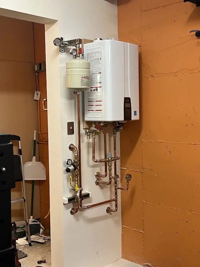 Plumbing technician inspecting water heater connections in Woodmoor